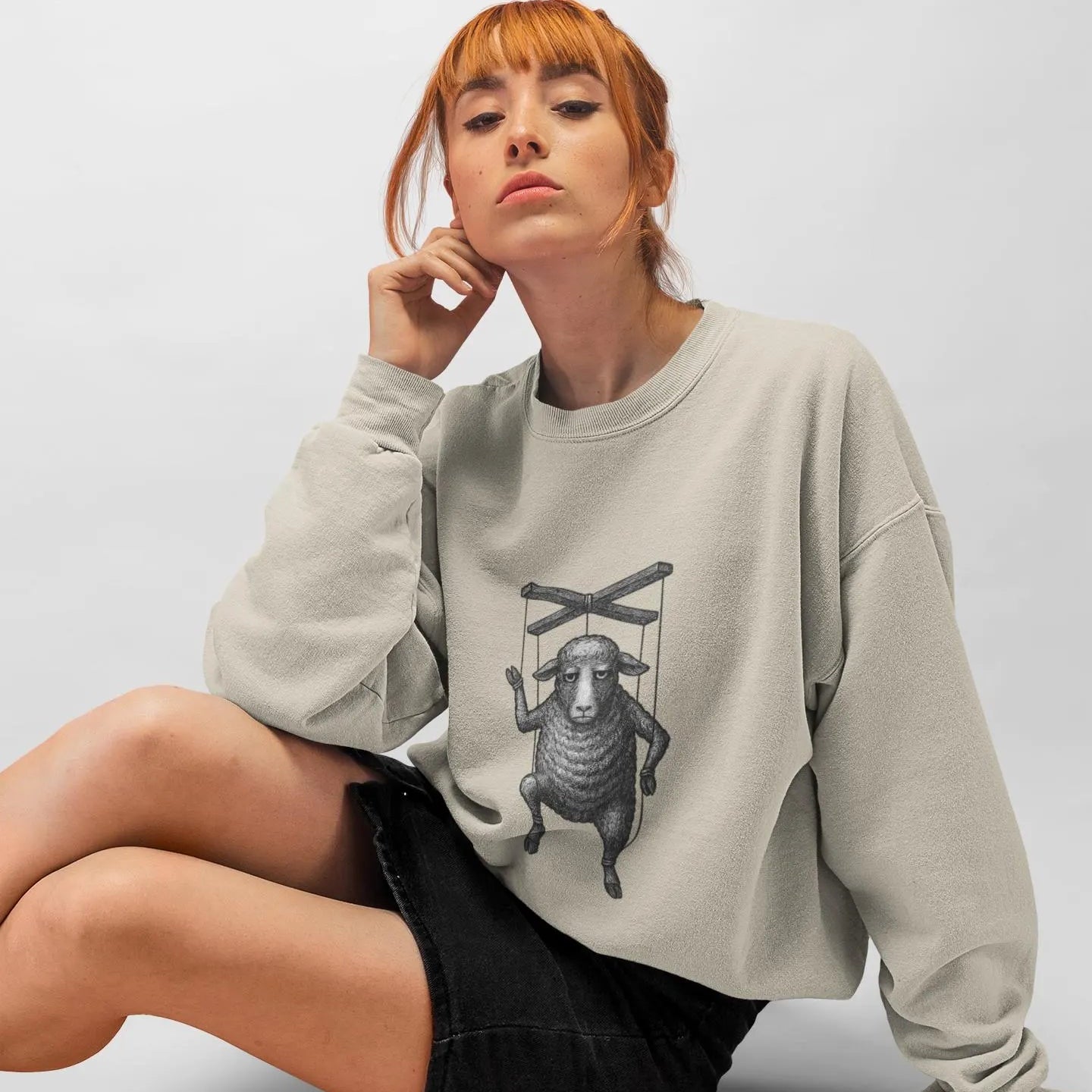 Person wearing a light gray sweatshirt with a graphic design on a white background
